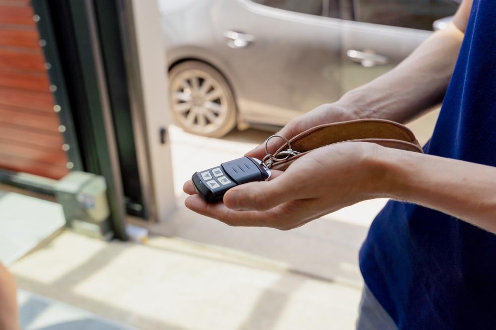 Hands holding a garage door opener with problems.