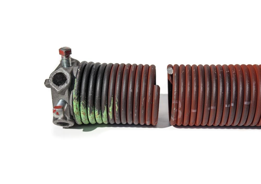 A close-up photo of broken garage door springs in two pieces.