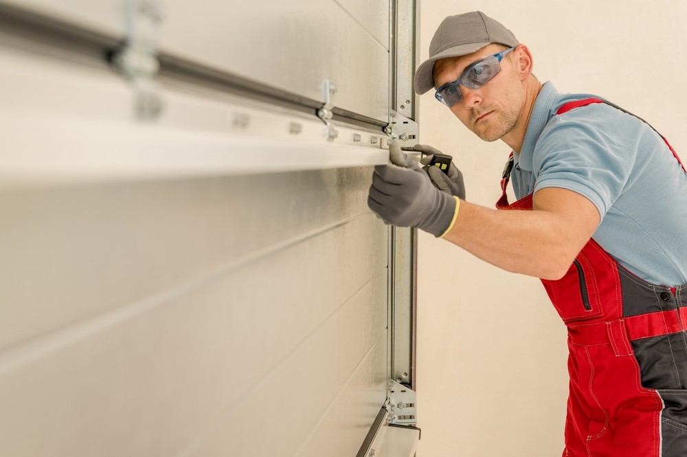 A technician in protective eyewear installing a new garage door.